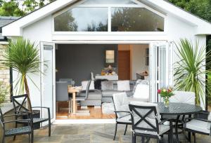 a patio with a table and chairs and a living room at Nos Da in Pencoed