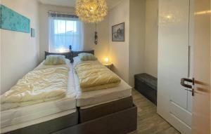 a bedroom with two beds with a chandelier at Stunning Apartment In Friedrichskoog Spitze With Kitchen in Friedrichskoog-Spitze