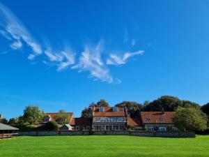 une grande maison avec un champ vert en face de celle-ci dans l'établissement Field Piece Cottage, à Burnham Market