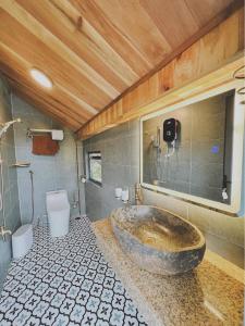 La salle de bains est pourvue d'une grande baignoire en pierre et de toilettes. dans l'établissement Mộc An Nhiên Farmstay, à Pleiku