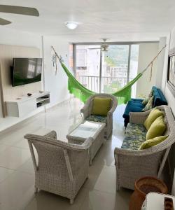 sala de estar con sillas, sofá y TV en Apartamento en el Rodadero, Confortable y amplio, con vista al mar, a 80mt de la playa, DELAMAR Apartmet, en Santa Marta
