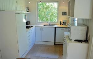 a kitchen with white cabinets and a sink and a window at Holiday Home Strandkrogen Ix in Dronningmølle