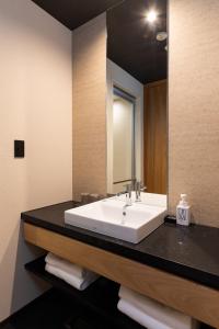 La salle de bains est pourvue d'un lavabo blanc et d'un miroir. dans l'établissement The358 SORA, à Fukuoka