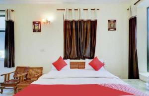 a bedroom with a large bed with red pillows at OYO Chaudhry Hotel in Hāthras
