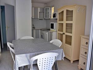 eine Küche mit einem Tisch und weißen Stühlen sowie einem Tisch und einer Küche in der Unterkunft Maison Marseillan-Plage, 4 pièces, 6 personnes - FR-1-387-196 in Marseillan