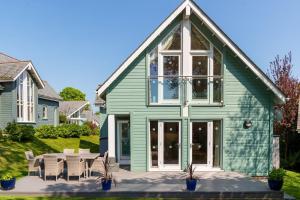 a green house with a table and chairs at Luxurious 3 Bedroom New England Style Villa - Trewhiddle V8 in St Austell