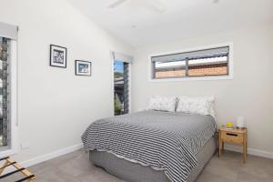 Taylors BeachTaylors Beach Cottage的一间白色卧室,配有床和2个窗户