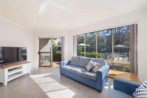 a living room with a blue couch and a tv at Martys No 5 in Nelson Bay