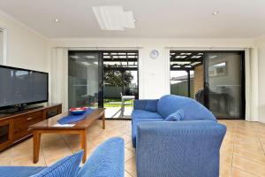a living room with a blue couch and a tv at Close to Little Beach and Shoal Bay Beach in Nelson Bay