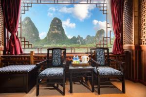 Zimmer mit 2 Stühlen und einem Tisch vor einem Fenster in der Unterkunft Li River Gallery Lodge in Yangshuo