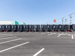 un estacionamiento con una fila de contenedores negros en HOTEL R9 The Yard Izumi en Izumi