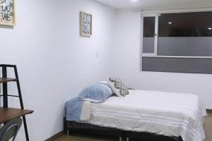 um quarto branco com uma cama e uma janela em Confortable, excelente ubicación em Tunja