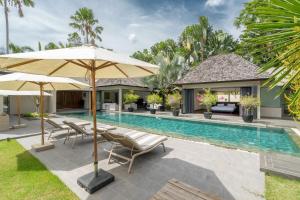 a swimming pool with chairs and umbrellas next to a house at Luxury 3BR Villa C Layan Estate: Idyllic Retreat near Beach in Layan Beach