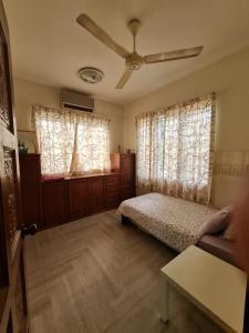 a bedroom with a bed and two windows at Al-Bayt Homestay in Ayer Keroh
