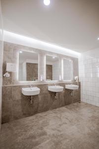 a bathroom with three sinks and two mirrors at Bobopod Juanda, Jakarta in Jakarta