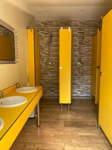 un bagno con due lavandini e bancarelle gialle di Albergue La HERMIDA a La Hermida