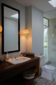 a bathroom with a sink and a toilet and a mirror at The Bed by The Sea in Canggu