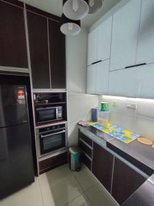 a kitchen with white cabinets and a black refrigerator at Da Best Guesthouse One Maxim Sentul Nice Cozy Condo 3 Rooms Aircond in Sentul KL in Kuala Lumpur