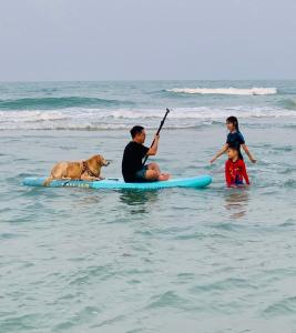 a man and two children and a dog on a surfboard in the ocean at Nichahome Luxury Villa in Hua Hin
