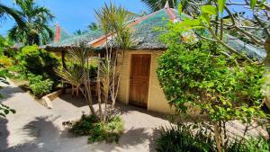 une petite maison avec une porte en bois dans le sable dans l'établissement Victory Seaside Home, à Île Bantayan