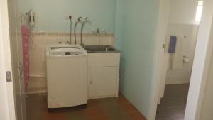 a small bathroom with a sink and a washing machine at Studio Apartment with Seaview in Airlie Beach