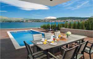 a table and chairs with a table and a swimming pool at Amazing Home In Okrug Gornji With 6 Bedrooms, Indoor Swimming Pool And Outdoor Swimming Pool in Trogir
