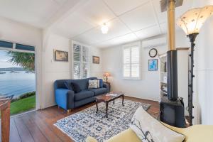 sala de estar con sofá azul y chimenea en Selby Cottage - Intimate Waterfront Getaway en Marks Point