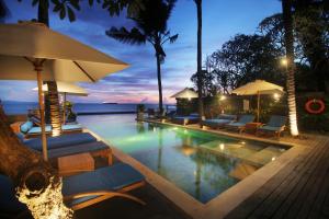 a swimming pool with chairs and umbrellas at a resort at Sagara Candidasa in Candidasa