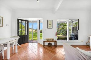 an open living room with a table and windows at Watta Cottage in Wattamolla