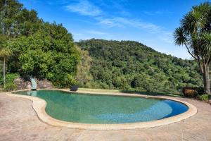a swimming pool with a mountain in the background at Watta Cottage in Wattamolla
