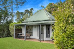a white cottage with a table in a yard at Watta Cottage in Wattamolla