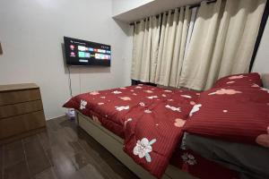 - une chambre avec un lit et une couverture rouge fleurie dans l'établissement Luxe Air Residences by Makati, à Manille