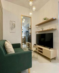 uma sala de estar com um sofá verde e uma televisão em Casa Feliz - Greenfield em Manila