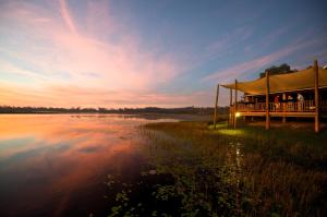 Wild Nature Lodge, Mareeba Wetlands في Biboohra: شرفة جلوس عليها ناس بجانب بحيرة