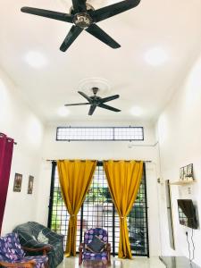 einen Deckenventilator im Wohnzimmer mit gelben Vorhängen in der Unterkunft Homestay Lestary near Taiping Fast WIFI Netflix in Taiping