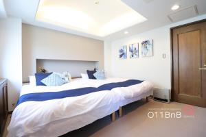 a bedroom with two beds with blue and white pillows at NK BLD3F Sapporo 3LDK 3BR 1 floor 1 room in Minami-jūichijō