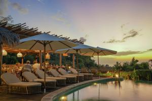 een restaurant met stoelen en parasols naast een zwembad bij Milo's Home in Jimbaran