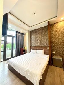 a bedroom with a large bed and a large window at Shine Hotel in Hue