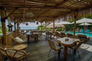 a restaurant with tables and chairs and a swimming pool at Milo's Home in Jimbaran