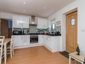 a kitchen with white cabinets and a wooden floor at Coachmans Cottage - Ukc2773 in Sandwich