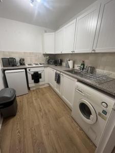 a kitchen with white cabinets and a washing machine at The Leith Walk Flat (just off) in Edinburgh