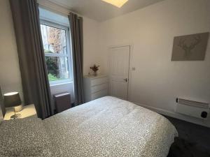 a white bedroom with a bed and a window at The Leith Walk Flat (just off) in Edinburgh