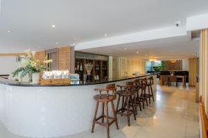 a bar with stools in a kitchen and a living room at Hotel De Karon in Karon Beach