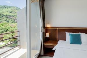 a bedroom with a bed and a balcony with a view at Hotel De Karon in Karon Beach