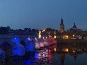 un puente sobre un río en una ciudad por la noche en Le petit Loir, gîte sur la Loire à vélo, 