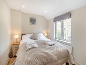 a bedroom with a bed and a window at Cherry Blossom Cottage in Etton