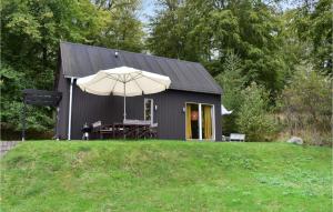 Östra Sönnarslöv的住宿－Lovely Home In stra Snnarslv With Kitchen，黑色棚子,上面有雨伞,桌子和雨伞