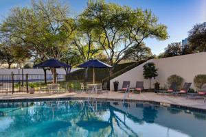 una piscina con sedie e ombrelloni accanto a un edificio di San Antonio Marriott Northwest Medical Center a San Antonio