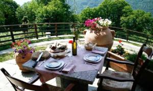 uma mesa com pratos e um vaso num pátio em Agriturismo La Fonte Di Mariella em Gravedona