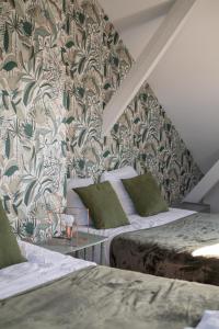 Cette chambre comprend 2 lits et un mur orné de papier peint à fleurs. dans l'établissement Grande maison à deux pas de la mer, à Bray-Dunes